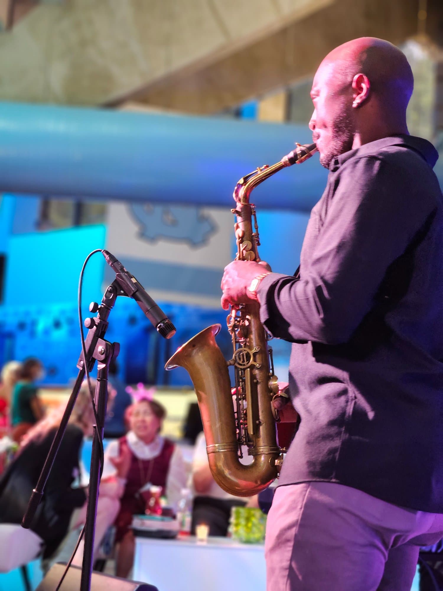 Saxophonist performing at an evening institutional concert with audience